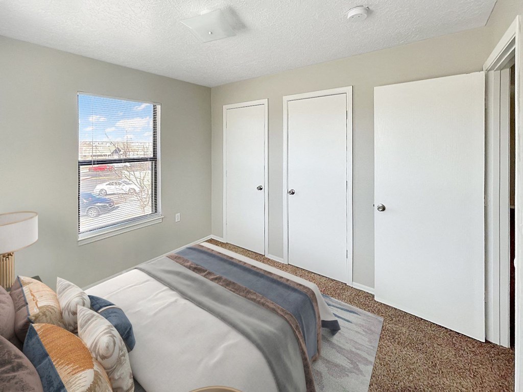 A bedroom with a bed, carpeted floor, and a window.